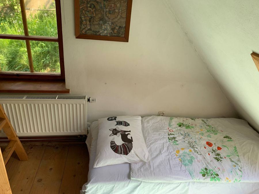 Pokoj v podkroví s postelí pod oknem do zeleně