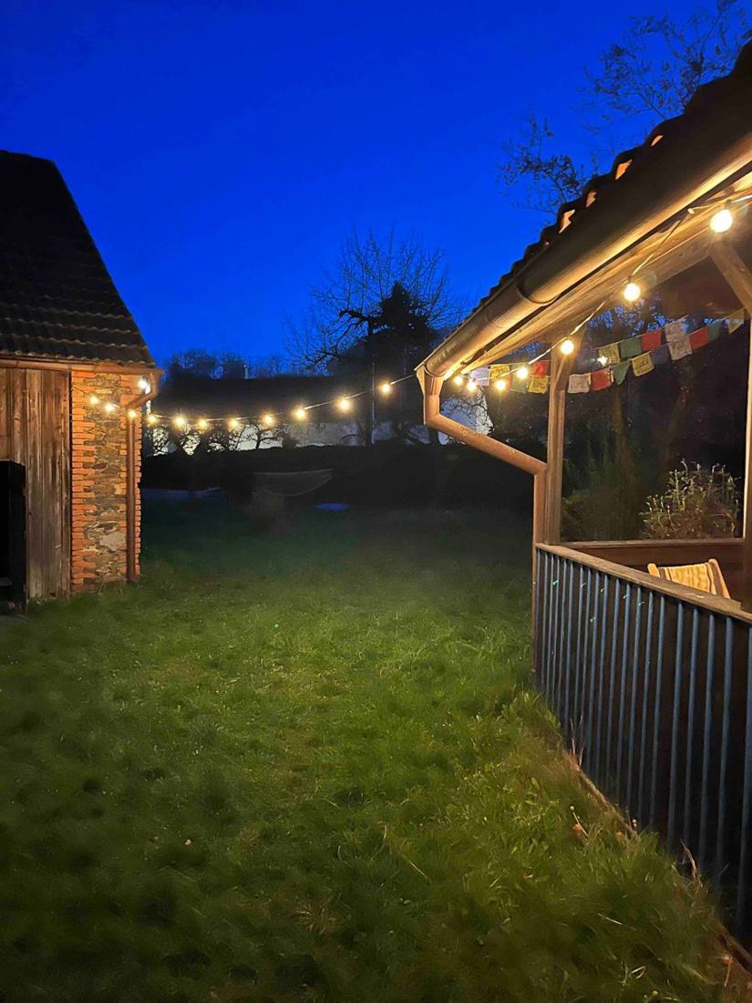 Řetěz světýlek nad verandou a zahradou za soumraku